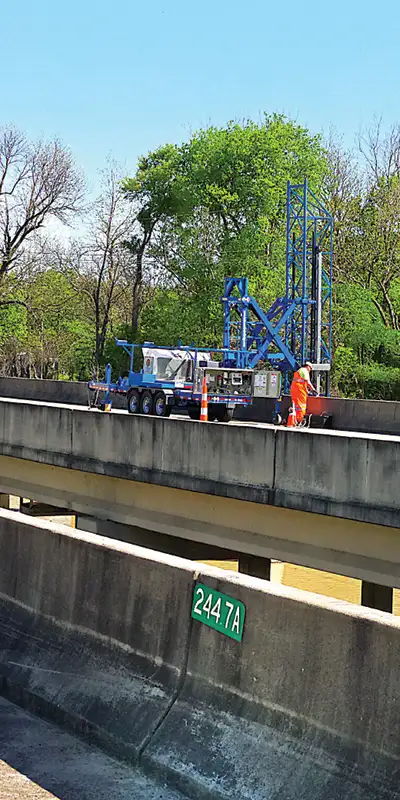 A lift being used to apply a repair under a bridge that has active flow beneath it, making access complicated
