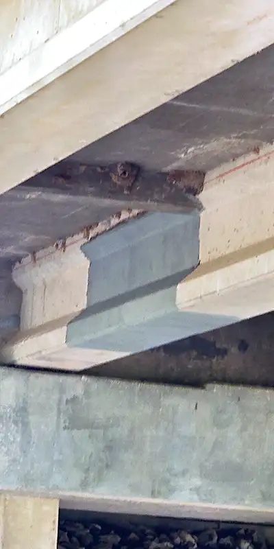 A portion of the underside of a bridge that has had the surface ground clean in preparation for a composite fiber fabric and epoxy application