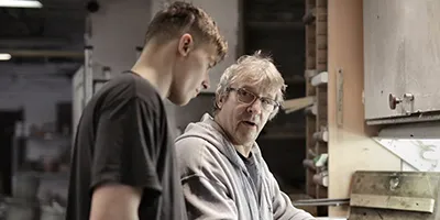 An older man explaining a process to a younger man