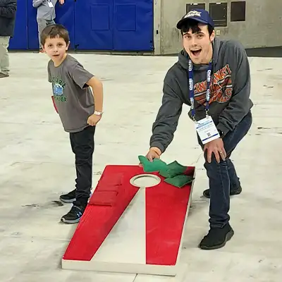 Caleb Rutledge playing corn hole at a trade show party with a kid