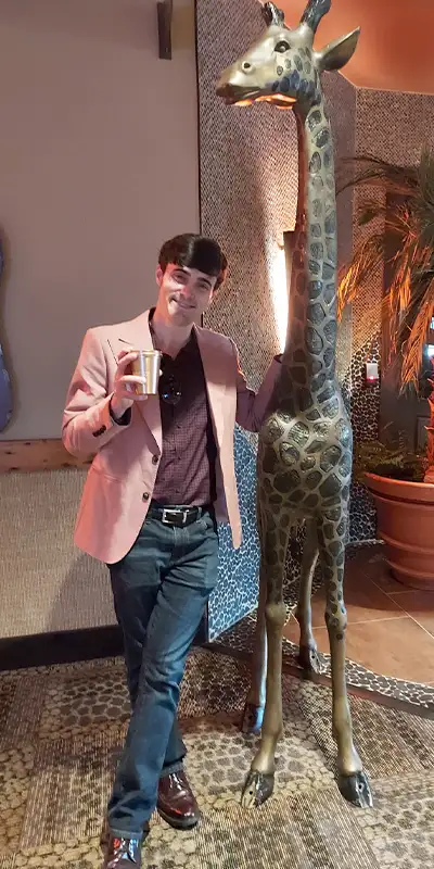 Caleb standing near a giraffe statue
