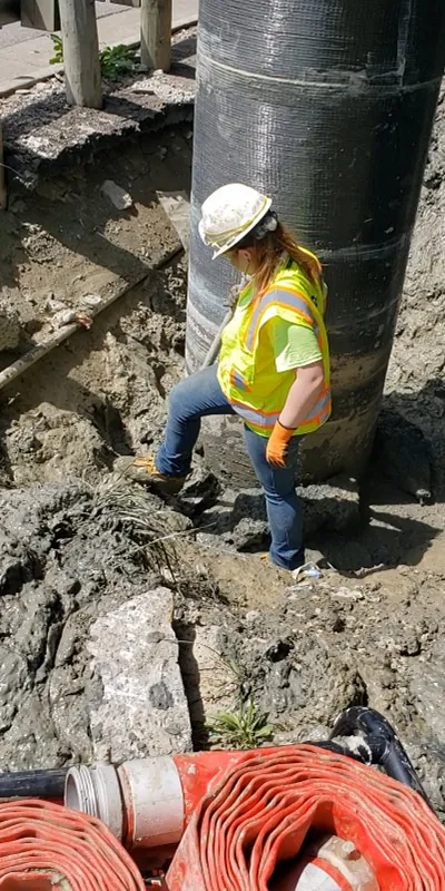 A technician digging mud away from the base of a bridge column
