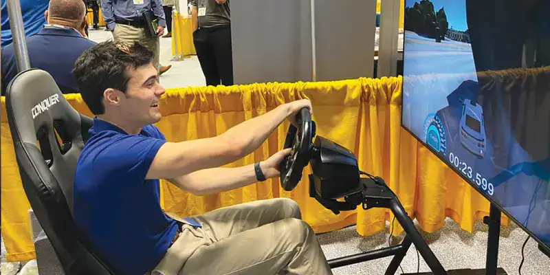 Caleb Rutledge sitting in a driving simulator at a tradeshow booth