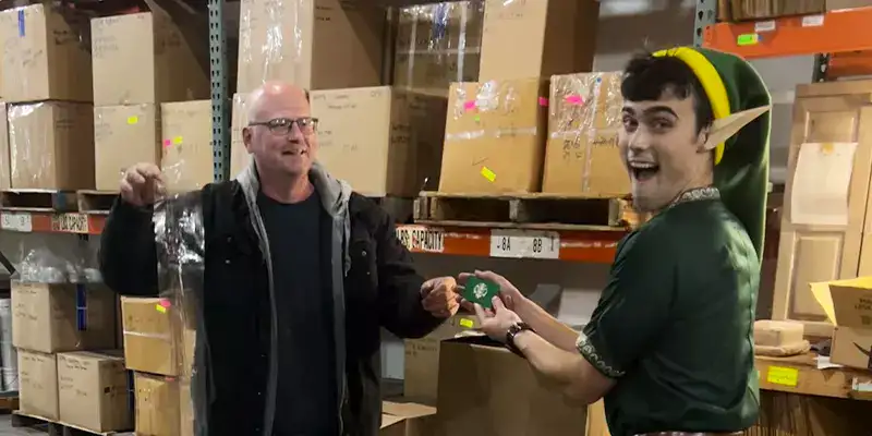 An employee dressed like an elf for halloween, handing a gift card to another employee