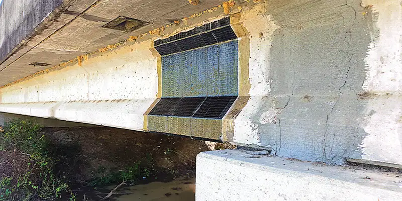 A portion of a bridge support that has been wrapped in a fiber fabric repair system
