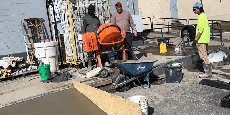 Several employees constructing a concrete ramp in the back lot