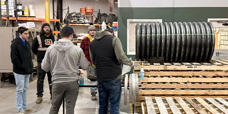 Several employees watching a HydraTite installation in a demo section of pipe