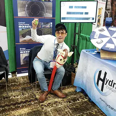 Caleb sitting at HydraTech's booth with a toy horse