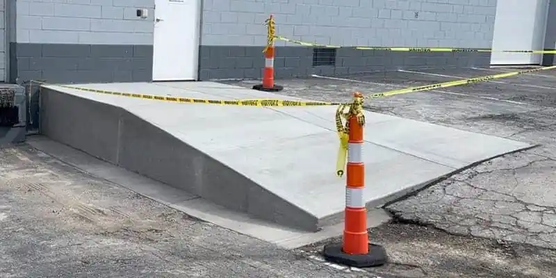 Traffic cones and caution tape marking a newly constructed concrete ramp