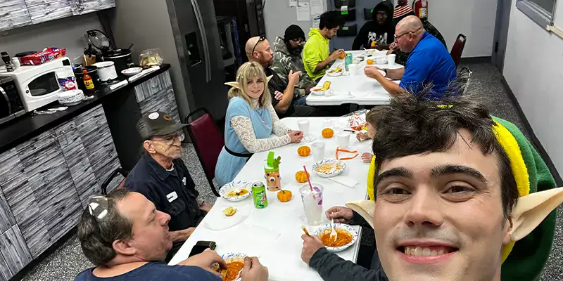 Several people sitting at lunch together, several of which are dressed up for halloween