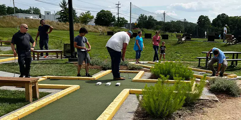 A group of HydraTech employees playing mini golf on a sunny day