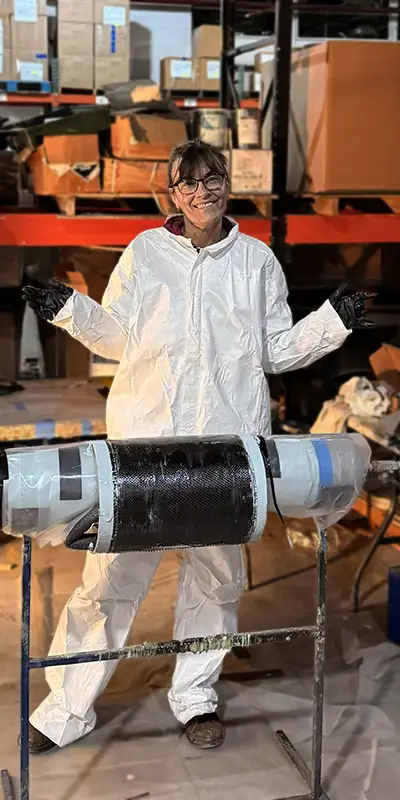 Jennifer standing behind a demo HydraWrap application. She is wearing a white tyvek suit