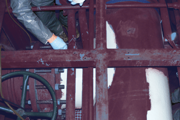 A large red tee fitting pipe that is being coated in epoxy