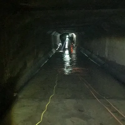 Long dark box culvert with technicians working on the joints far in the distance