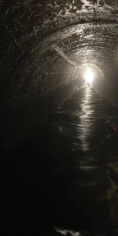 Looking down a long dark tunnel with a light at the end of it.