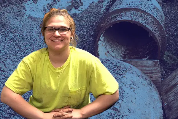 A woman sitting in front of a pipe entrance