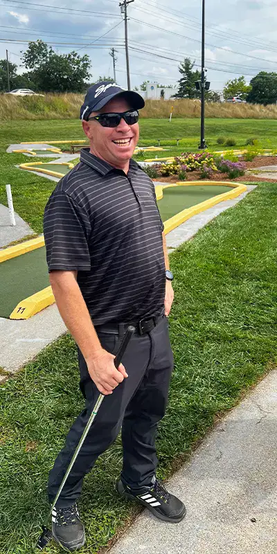 Mike Albert, smiling in front of a mini golf course