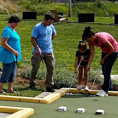 A group of HydraTech employees helping a child play mini golf