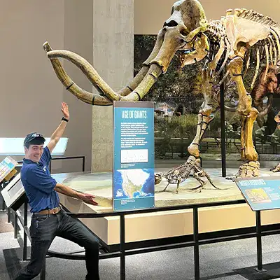 Caleb motion to a mammoth skeleton in a museum