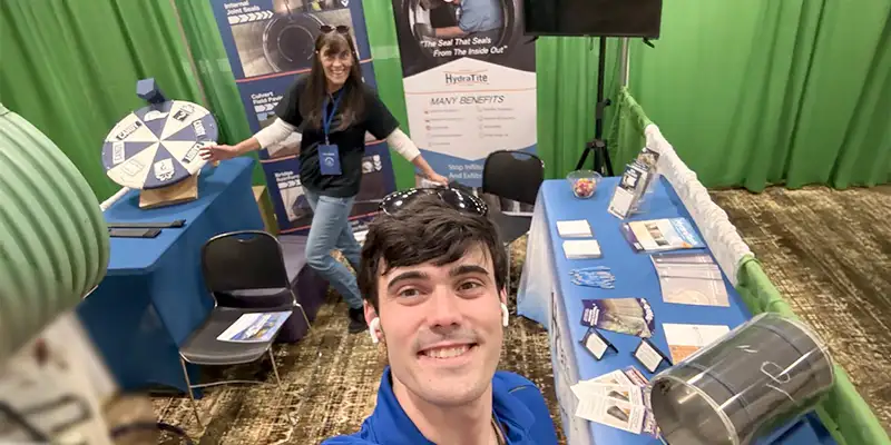 Caleb taking a selfie of himself and Jennifer at the HydraTech trade show booth