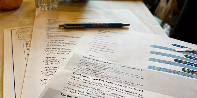 Several papers on a table with Christmas themed games for the yearly HydraTech Christmas party