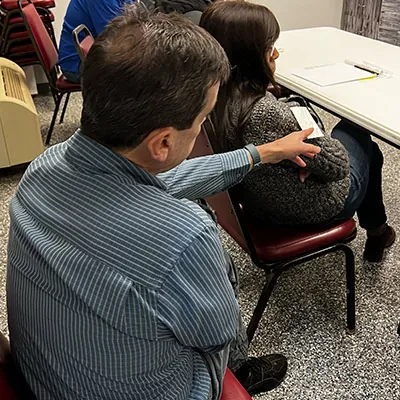 A person sitting in on a first aid training passing a medical example to another employee