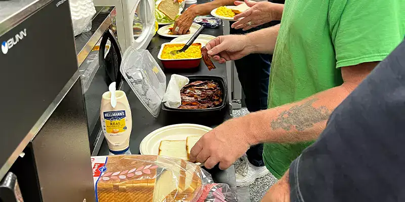 A line of food at a potluck being selected from by employees