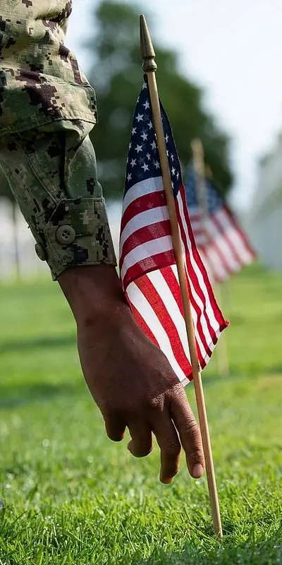 A soldier placing a mini flag at a cemetery