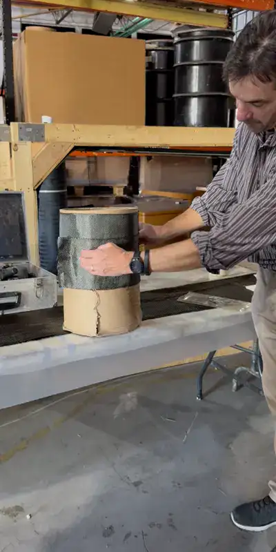 Placing dry carbon fiber fabric on a cardboard pipe to demonstrate how it will lay during the actual application process