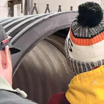 Two people looking into a demo section of pipe where a HydraTite seal is being installed to showcase the process