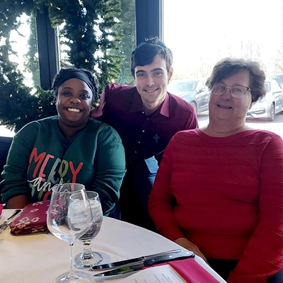 Three employees smiling at the yearly Christmas lunch