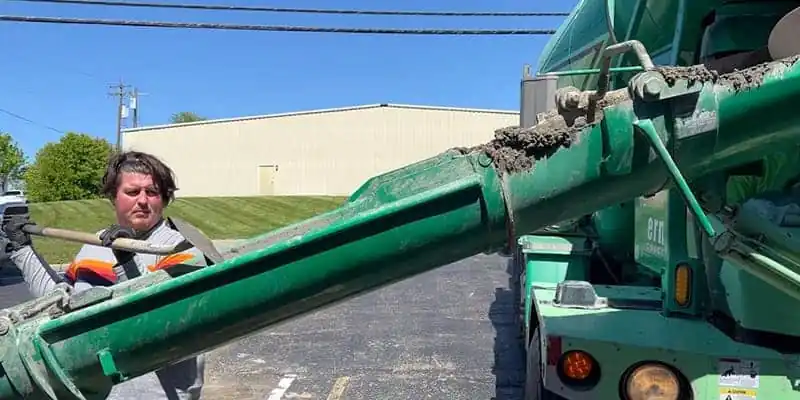 A technician shoveling concrete down a shoot