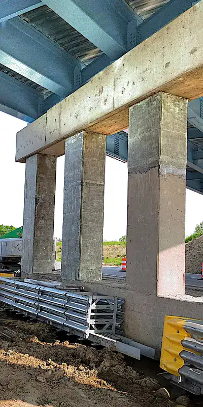 Three bridge support columns partially wrapped in a fiber wrap repair