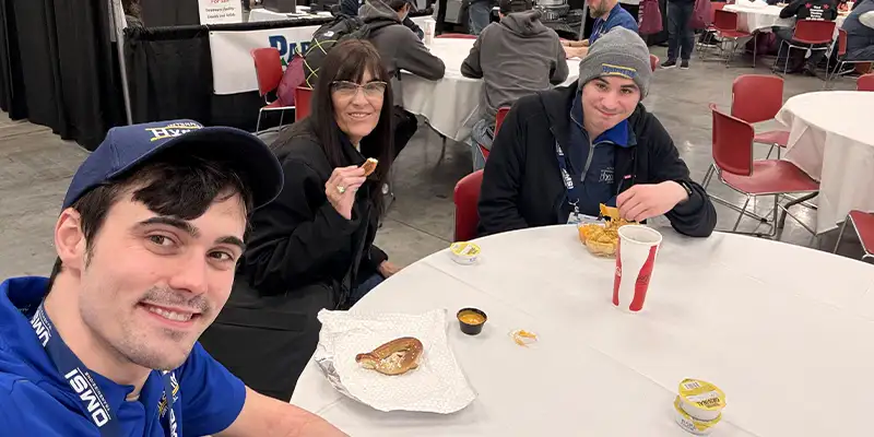 Caleb taking a selfie of himself, Jennifer and Will at a trade show lunch