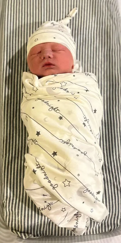 A small baby swaddled, laying in a bed