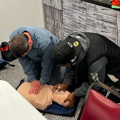 Two HydraTech employees practicing CPR on a first aid dummy