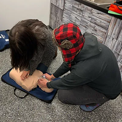 Two HydraTech employees practicing CPR on a first aid dummy