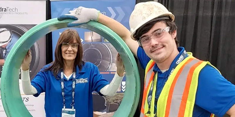 Caleb and Jennifer near the HydraTite internal pipe joint seal demo seal installation at the WWETT Show