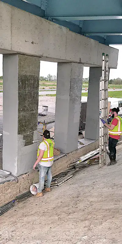 Applying a coating to a row of newly wrapped bridge support columns