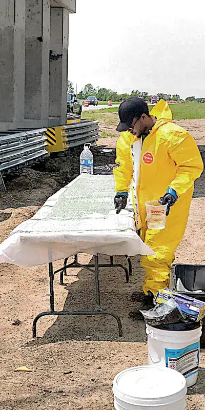 Technicians preparing to apply a fiber wrap fabric to a bridge to reinforce its supports