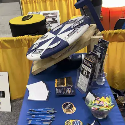 A prize wheel and various other tradeshow stuff on a table at a booth