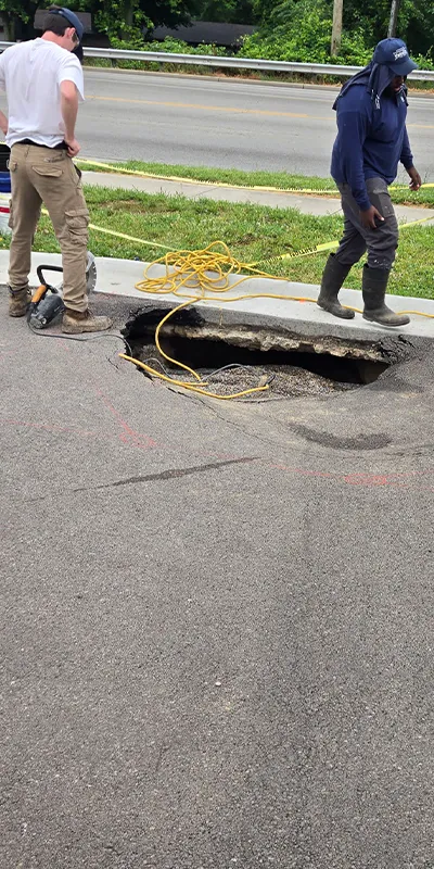 Field service crew members standing near a  sinkhole