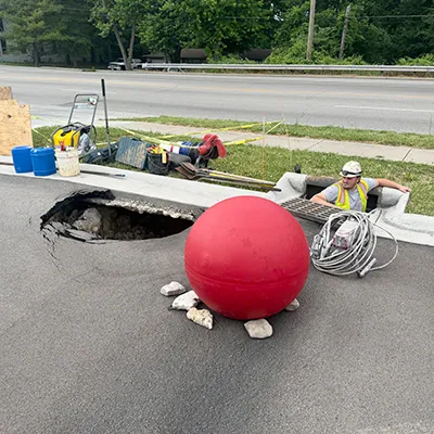 A field services technician entering a manhole to start repairing the compromised point below ground that has led to the formation of a sinkhole