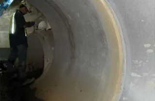 A technician working inside a reinforced concrete storm drain