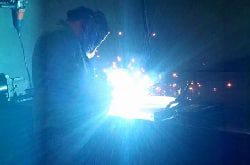 A person welding metal with a bright blue light