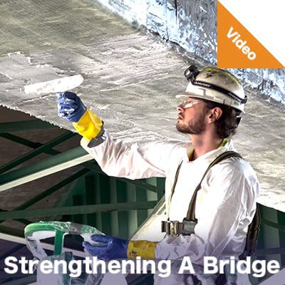 A technician applying epoxy to the underside of a bridge