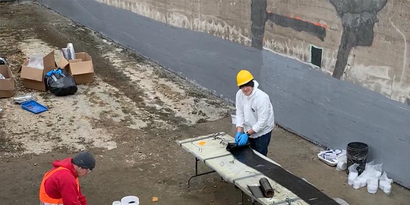 Two people in a hydraulic jump that has been dewatered and shut down, preparing to apply HydraWrap