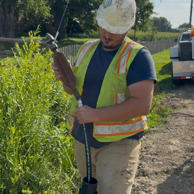 A field technician connecting pieces of a hose so that a jettervac can be used to clear out a culvert