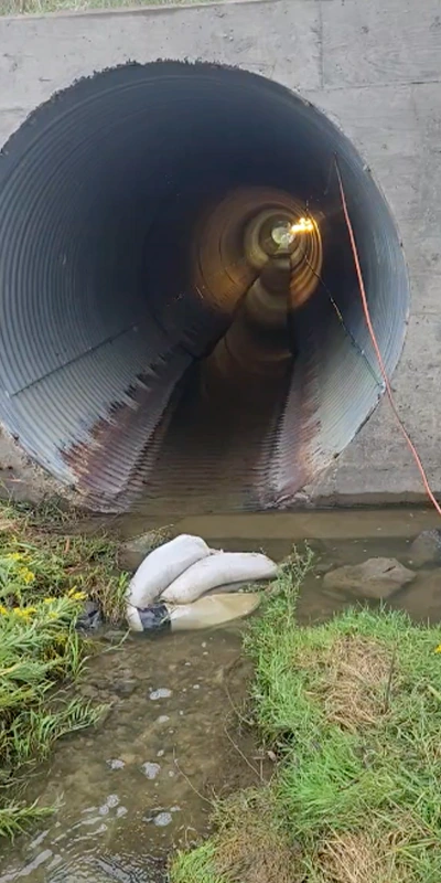 An entrance to a large-diameter pipe that has rusted along the bottom