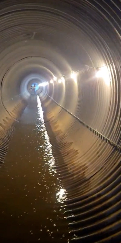 A corrugated metal pipe that has had its invert paved in a layer of concrete